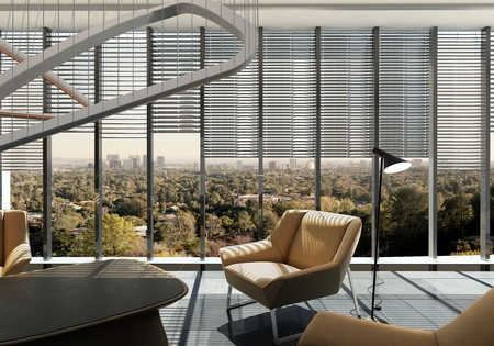 Modern living room in a suburban apartment overlooking a leafy green city furnished with...