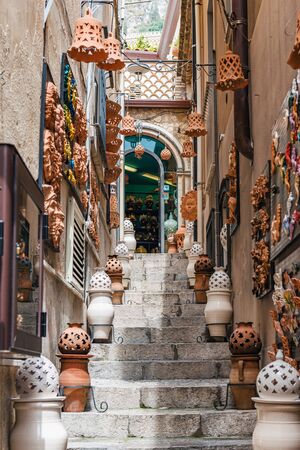 Clay or earthenware containers and decorations on a narrow steep stone staircase in Taormina, Sicily leading to an arched window at the topのeditorial素材