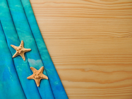 Yellow wooden background with turquoise cloth with starfish and copy space.の写真素材