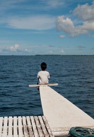 boy looks out to sea from boatの写真素材