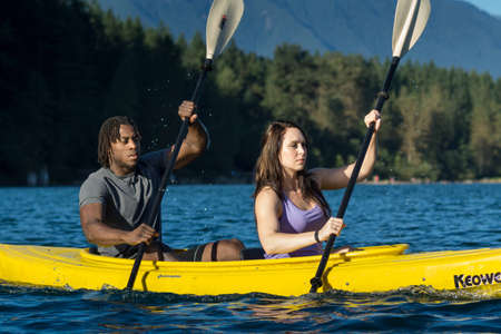 Couple paddling in kayak on lake.
