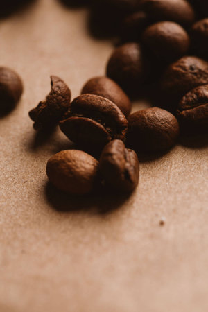 dark coffee beans close-up on light paper close up.