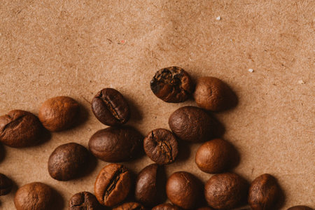 dark coffee beans close-up on light paper close up.