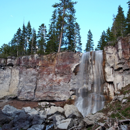Paulina Falls in the Newberry National Volcanic Monument in Central Oregon rushes over a cliff in a forest of trees on a summer evening.の写真素材