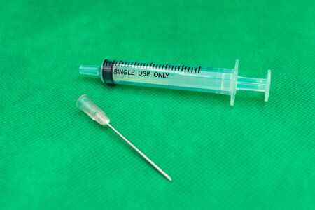 Syringe on green wallpaper.A medical device that is used to inject fluid into, or withdraw fluid from, the body. A medical syringe consists of a needle attached to a hollow cylinder.の写真素材