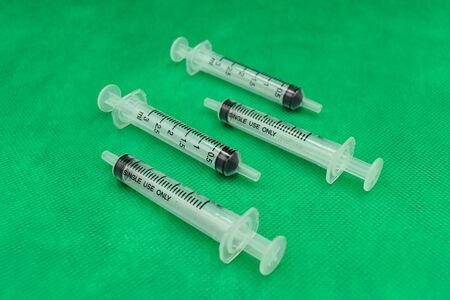Syringe on green wallpaper.A medical device that is used to inject fluid into, or withdraw fluid from, the body. A medical syringe consists of a needle attached to a hollow cylinder.の写真素材