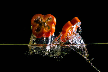chopped pepper dropped into water and created a water splashの写真素材