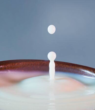 drop of milk falling into a cupの写真素材