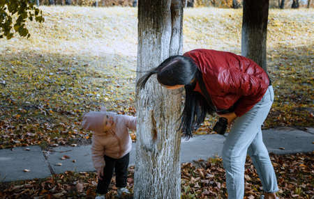 The child hides behind a tree from the photographer so as not to take pictures