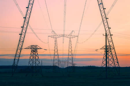 A line of power poles standing in a field and going into the distance beyond the horizon.