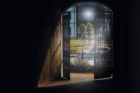 Decorative wrought-iron gates open to a sunny courtyard, highlighting the beauty of historic architecture.の写真素材