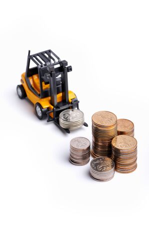 Yellow toy forklift moving stocks of coinsの写真素材