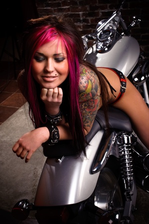 Attractive tattooed girl sitting on a big chopper, smiling