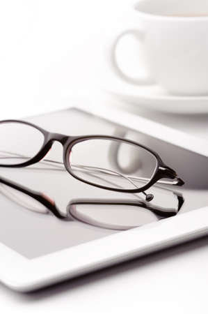 Still life with white tablet, coffee cup and glasses on a white tableの写真素材