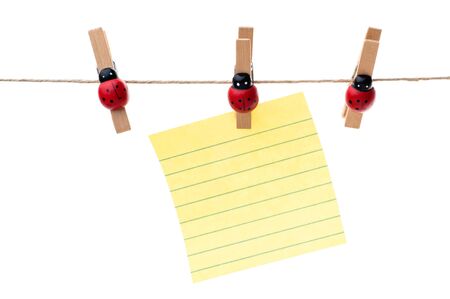 Yellow note hanging on a clothesline, three pins, white backgroundの写真素材