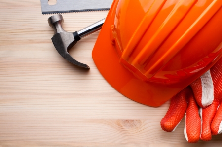 Hardhat, gloves and some assorted tools arranged on a wooden surface. Construction, repair or home improvement background.の写真素材