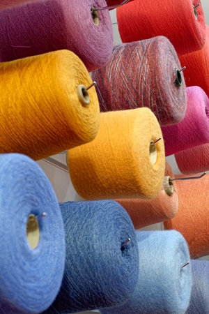Assorted spools of multi-colored wool threads, abstract textile industry background