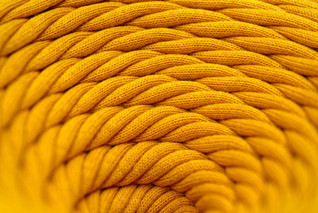 Skein of yellow braided synthetic cord, close-up shot, selective focus, abstract textile industry backgroundの写真素材