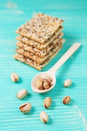 Pistachios on wooden spoon and biscuits with assorted seeds over wooden vintage background.の写真素材
