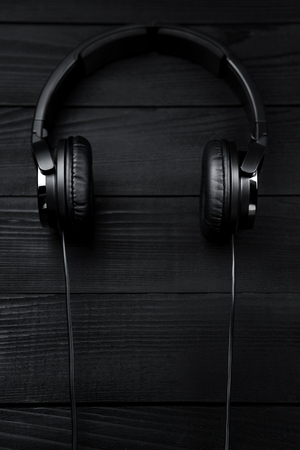 Black headphones on black wooden dark background.の写真素材