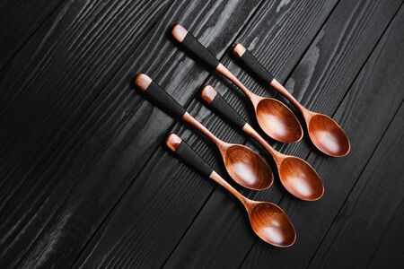 Wooden vintage spoons on the black wood background.の写真素材