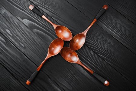 Wooden vintage spoons on the black wood background.の写真素材