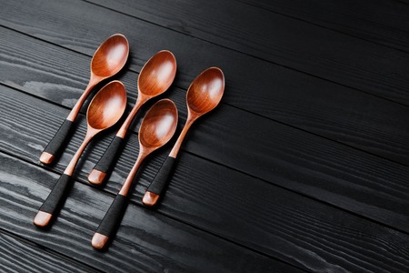 Wooden vintage spoons on the black wood background.の写真素材