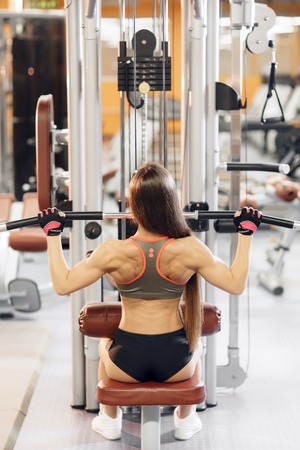 Young woman working at the lat pulldown machine in the gym,