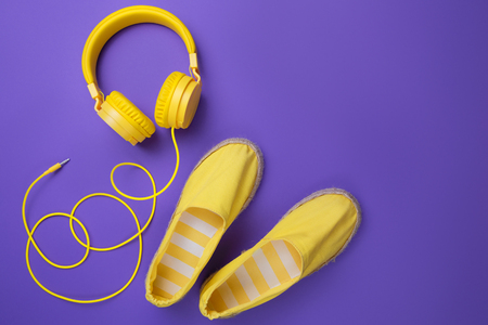 Yellow headphones and summer shoes on purple background. Summer music concept.の写真素材