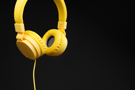 Yellow headphones on dark black background. Music concept.の写真素材