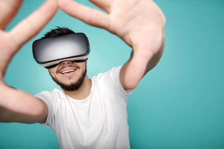 Attractive bearded man trying VR headset and exploring another world on the colorful background.の写真素材