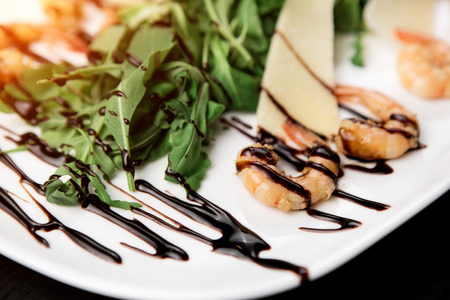 Tasty shrimps on a plate with cheese and rucola leaves on black wood background.の写真素材