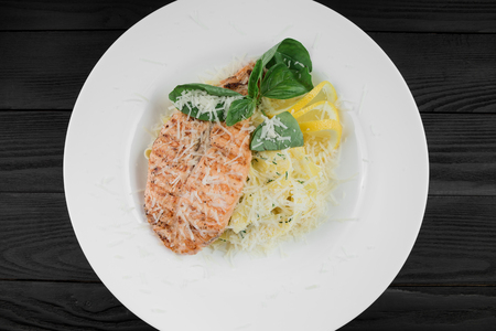 Pasta with grill salmon, parmesan and lemon on a white plate. Top viewの写真素材