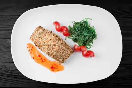 Grilled salmon with potatoes and sauce on white plate.の写真素材