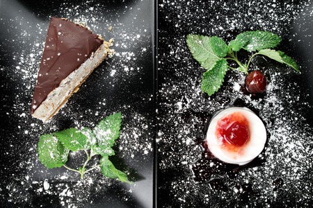 Photo of italian panna cotta dessert with strawberry sirup and cake with nuts and chocolate on the black plate on dark wooden background.の写真素材