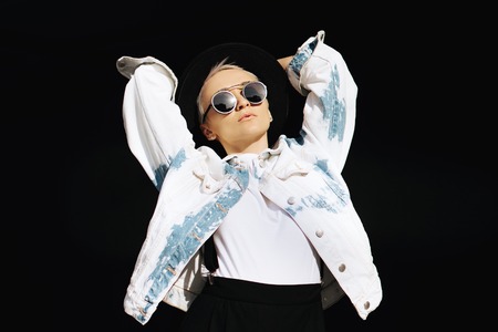 Cheerful attractive hipster girl enjoying leisure time. Bright young woman in stylish outfit is posing in dark shadow.の写真素材