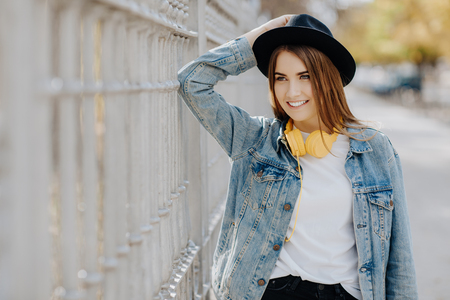 Close up portrait of a beautiful smiling girl with brown hair wearing a hat outdoorsの写真素材