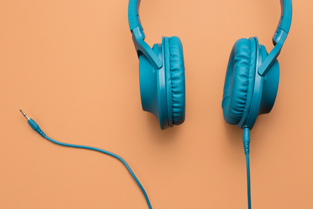 Close-up photo of stylish modern blue cyan headphones over beige background.の写真素材