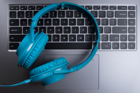 Photo of stylish modern computer or notebook and blue cyan headphones over beige background. Close-up.の写真素材