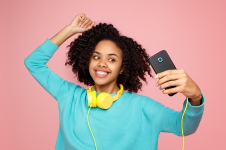 Attractive african american young woman with bright smile dressed in casual clothes take picture...