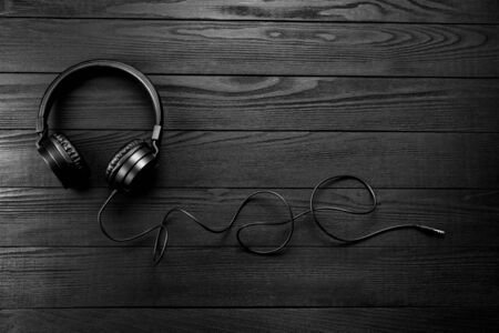 Black headphones on black wooden dark background.