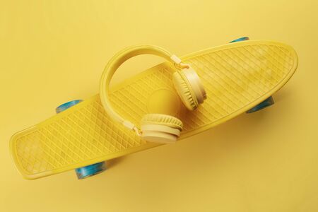 Yellow headphones and skateboard or pennyboard on yellow background. Music concept.の写真素材