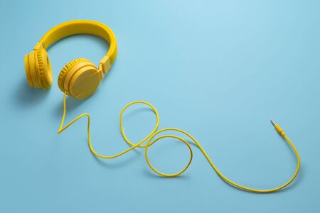 Yellow headphones on blue background. Music concept.の写真素材