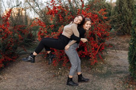 Beautiful two young twin sisters in casual outfit with bright smile have fun at the park. Family...