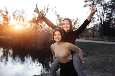 Positive two young twin sisters in casual outfit with bright smile posing at the park. Freedom concept.の写真素材