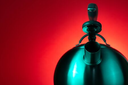 Close-up photo of stainless steel kettle in neon light over red background.の写真素材