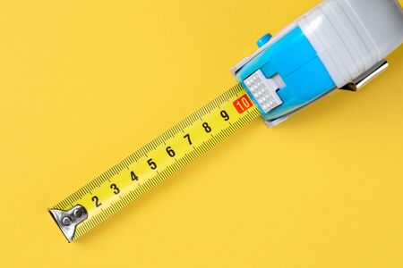 Measuring tape isolated over yellow bakground. Carpenter and Construct concept.