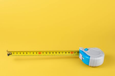 Measuring tape isolated over yellow bakground. Carpenter and Construct concept.
