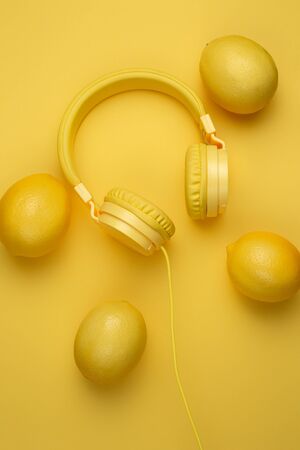 Yellow headphones decored with lemons on yellow background. Music concept.の写真素材