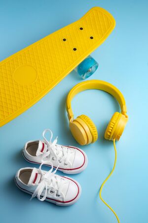 Yellow headphones, white sneakers and traditional style soccer ball over yellow background.の写真素材